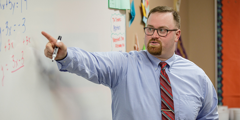 Teacher pointing to a lesson on a whiteboard