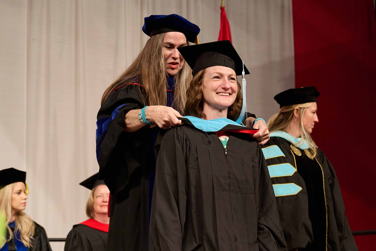 Dr. Julie Merriman presents a counseling graduate with her hood