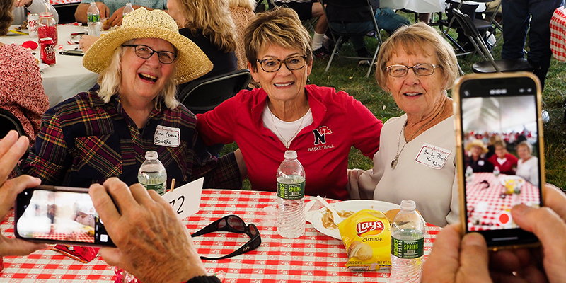 Three alumni pose for a photo during the tailgate picnic