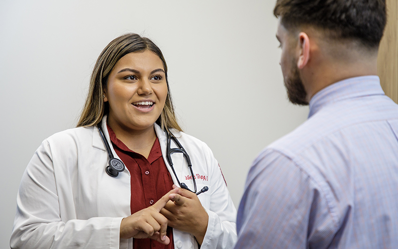 A female physician assistant student meets with a patient during a mock clinic