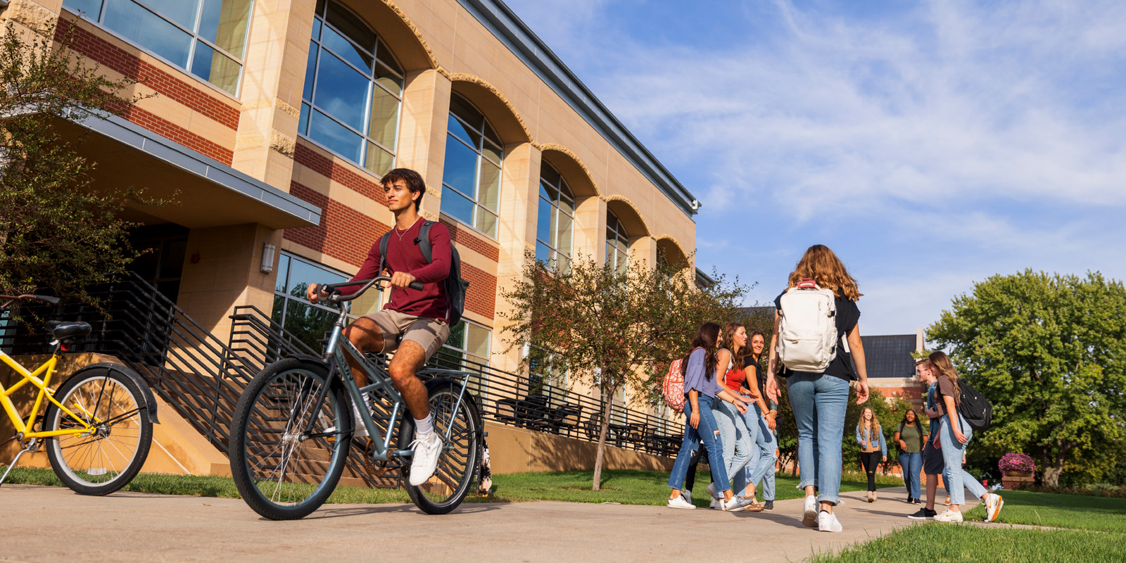Students walk and ride bike past the DeWitt Learning Commons
