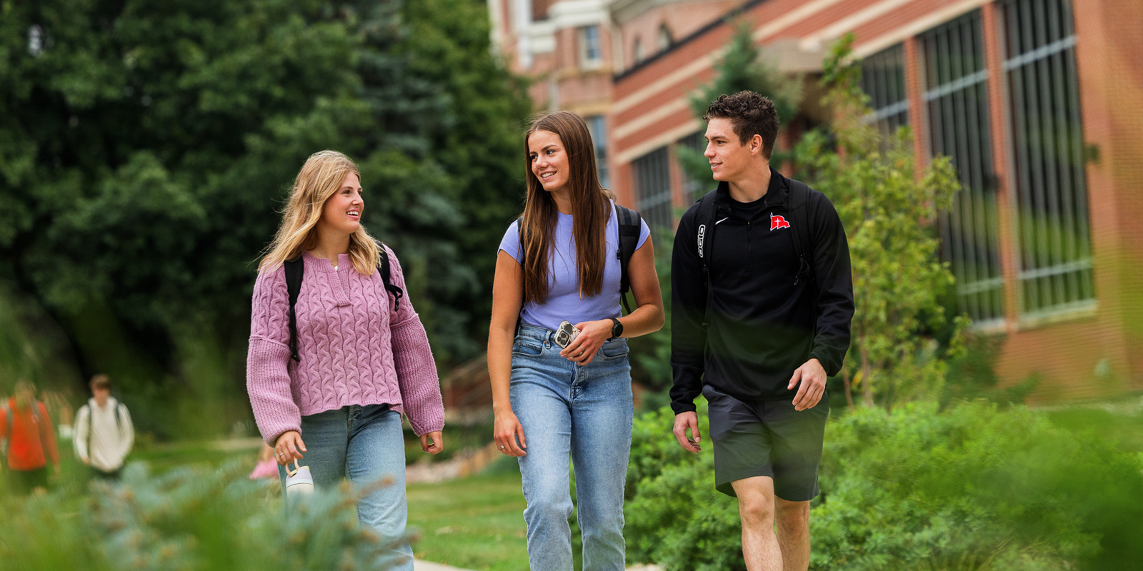 Two female students and one male student walking across campus