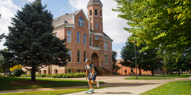 Student riding a skateboard in front of Zwemer Hall