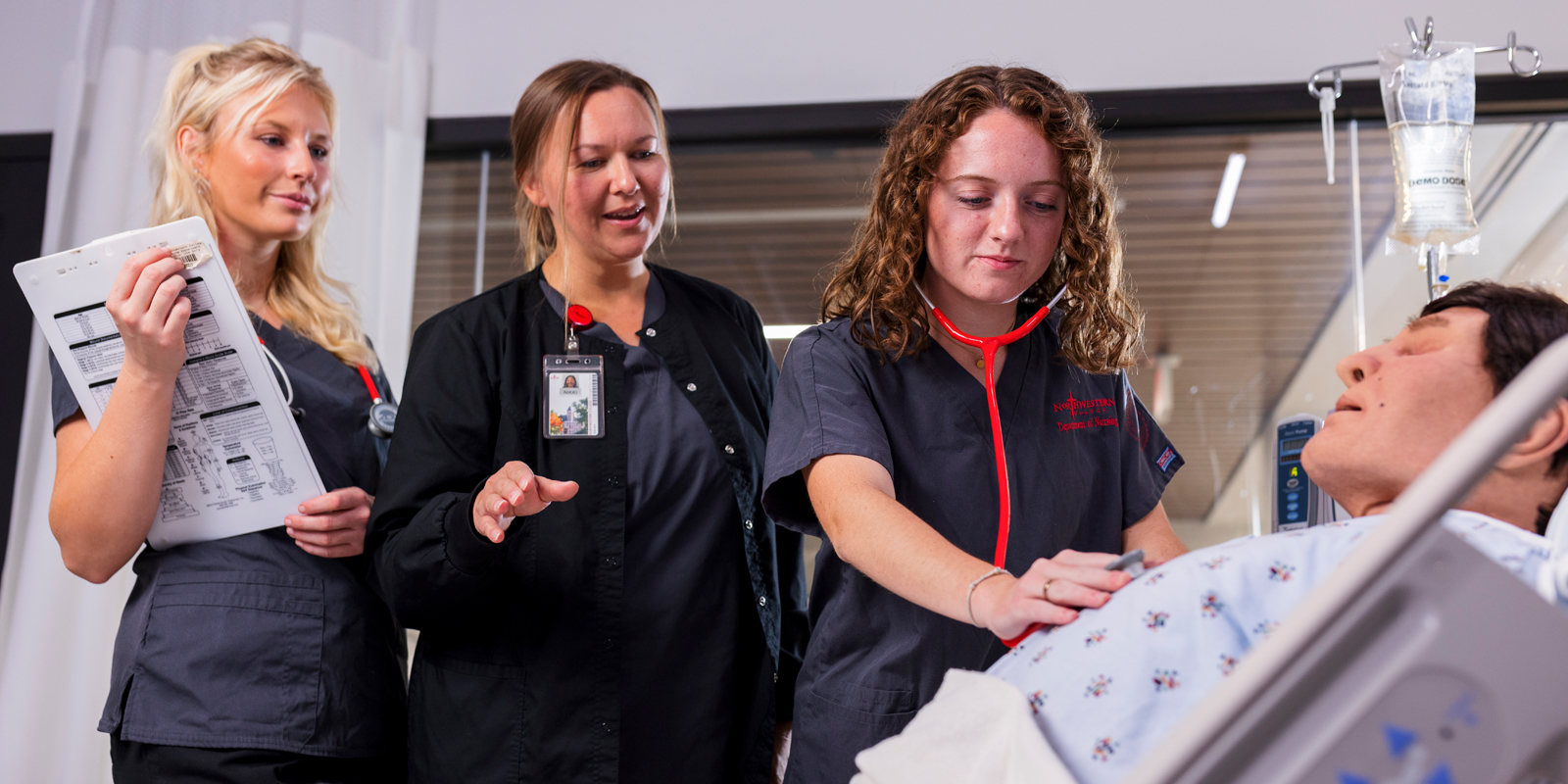 Two nursing students and a professor practice clinical skills during a simulation