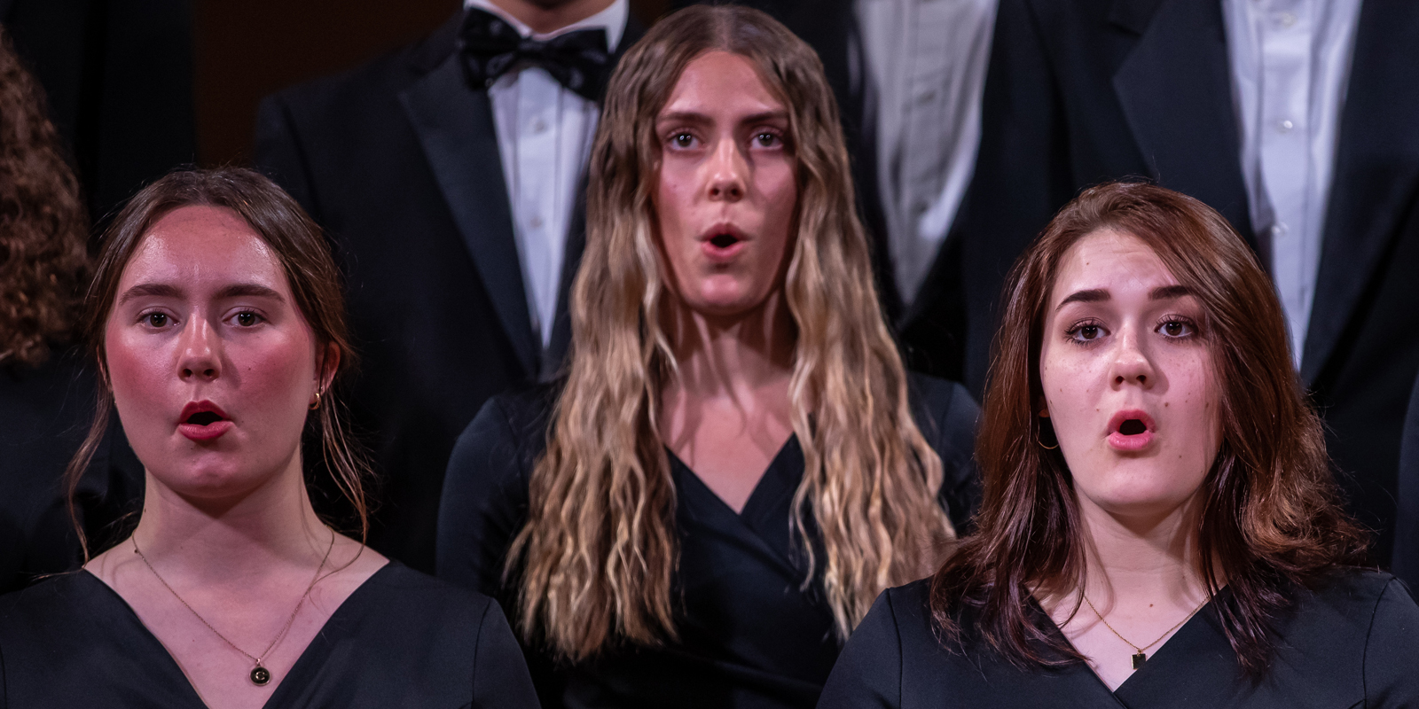 Three female students singing in a choir