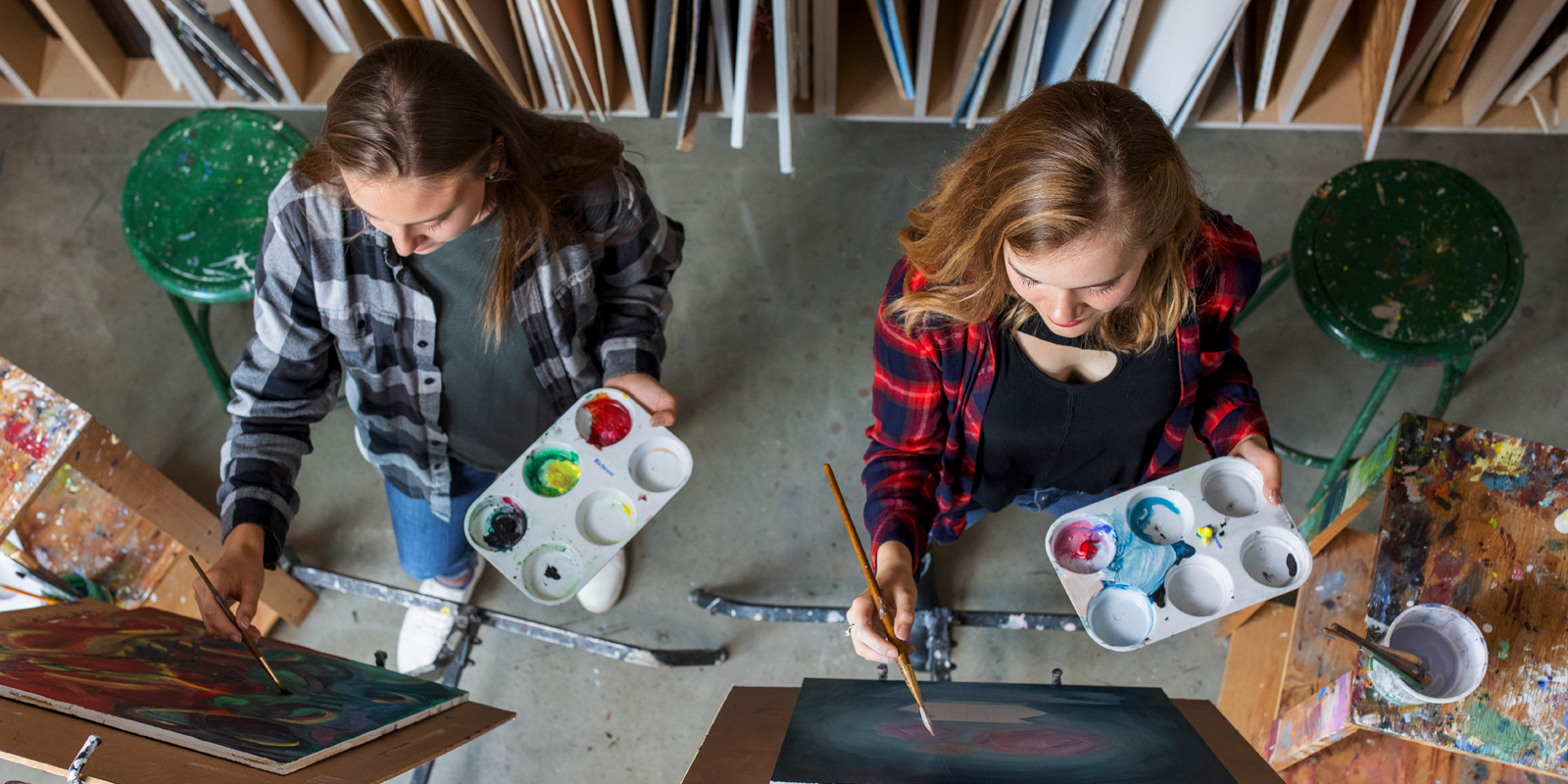 Two female students painting at easels in an art studio