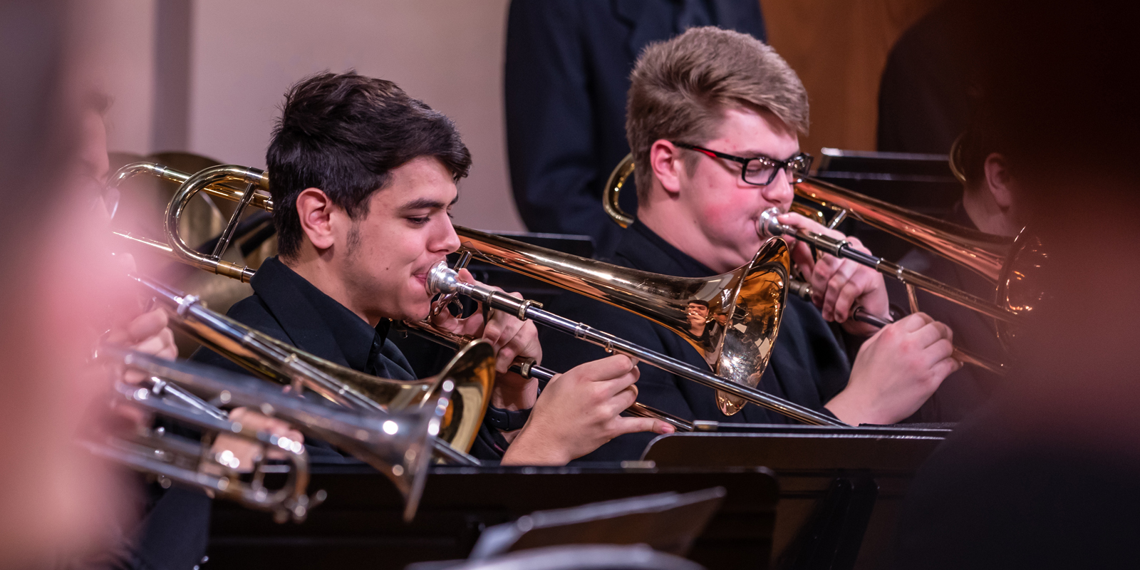 Two male students playing trombone at a concert